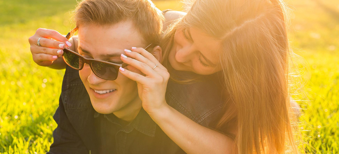 Glückliches Paar im Sonnenlicht, lachend und verspielt – symbolisiert einen positiven Neuanfang nach einer Beziehungspause.